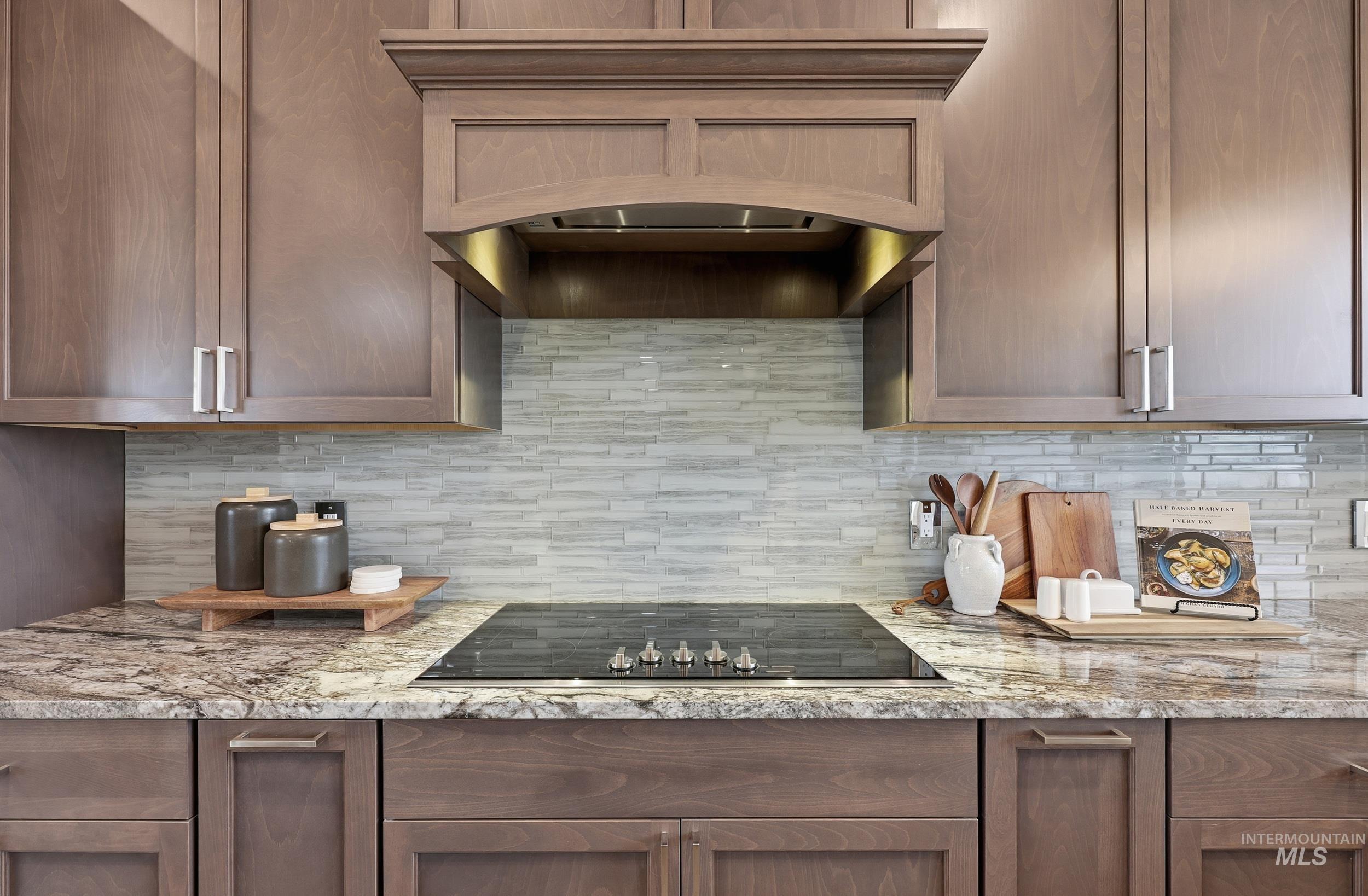 9264 Basin Kid Court Middleton, ID 83644 - Photo 7 of 50 Kitchen with custom range hood, light stone countertops, decorative backsplash, and black electric stovetop
