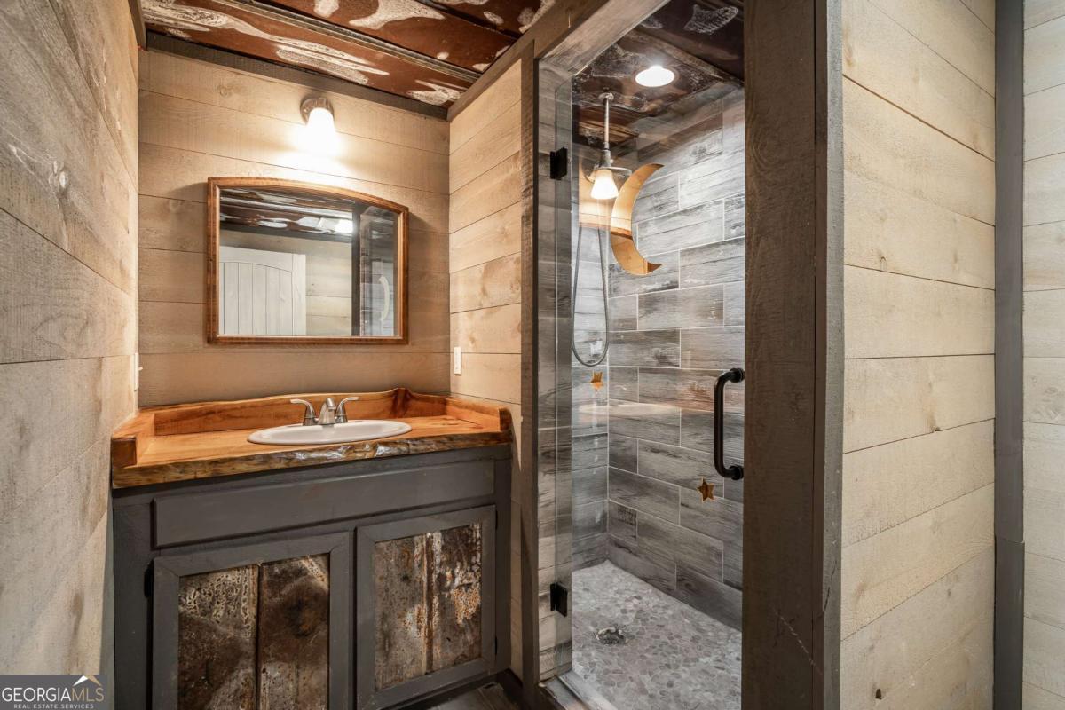 2637 River Road Mineral Bluff, GA 30559 - Photo 35 of 69 a bathroom with a granite countertop sink a mirror and shower