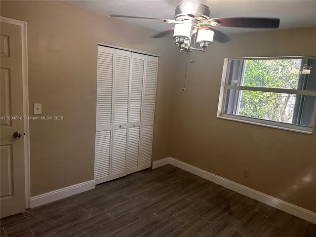 an empty room with wooden floor chandelier and windows