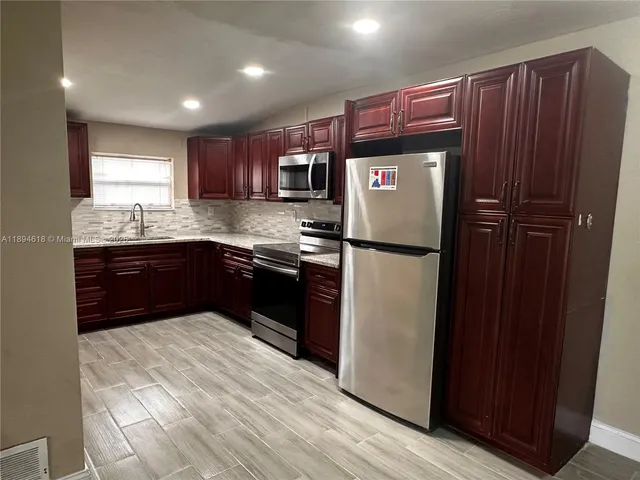 a kitchen with stainless steel appliances granite countertop a refrigerator and a sink