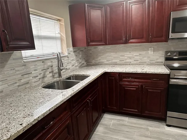 a kitchen with granite countertop stainless steel appliances wooden cabinets and a sink