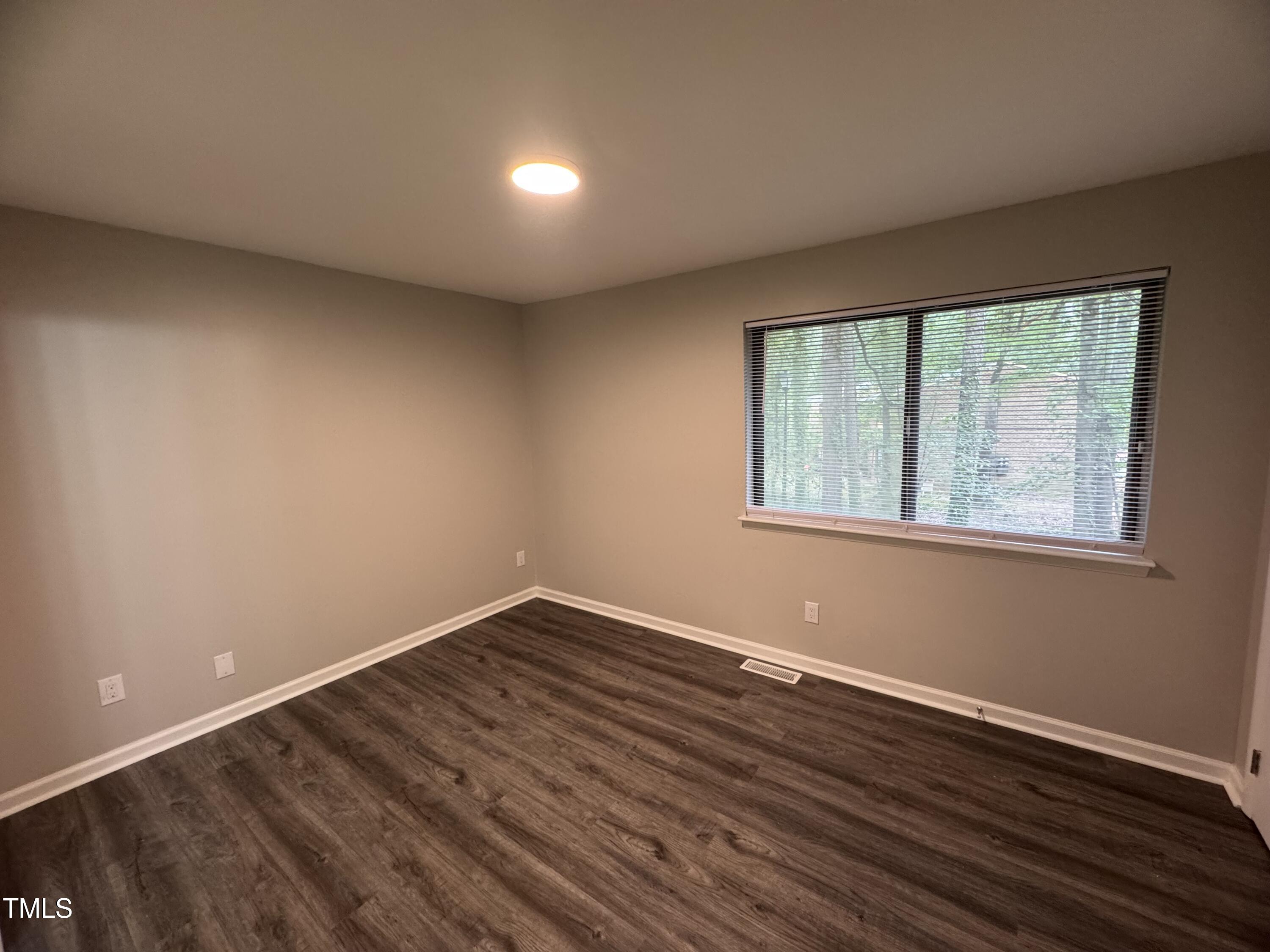 1222 Teakwood Place Raleigh, NC 27606 - Photo 8 of 15 a view of an empty room with wooden floor and a window