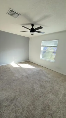 an empty room with windows and fan