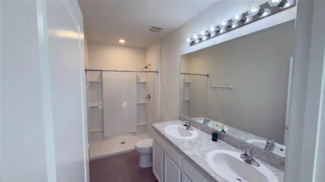a bathroom with a double vanity sink mirror and toilet
