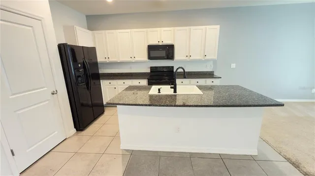 a kitchen with granite countertop a refrigerator a stove a microwave and a sink