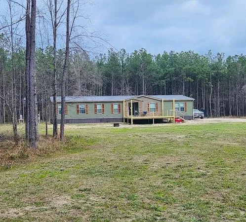 a front view of house with yard and trees in the background