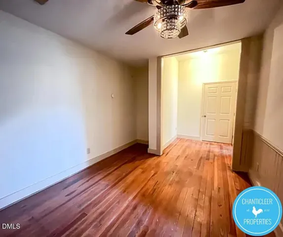 a view of an empty room with a window and wooden floor