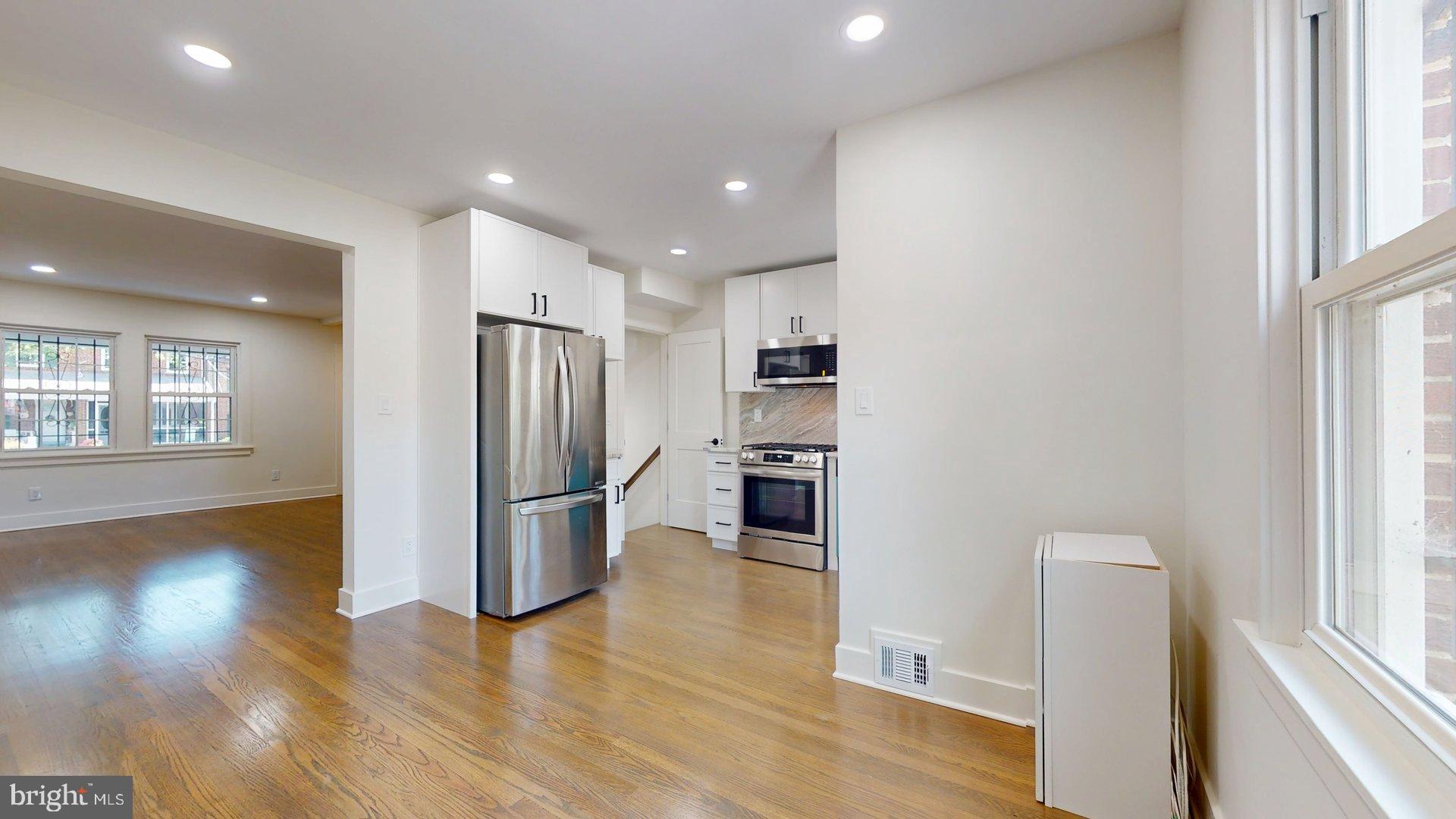 38 Crittenden Street Northeast Washington, DC 20011 - Photo 9 of 48 an empty room with wooden floor and a kitchen