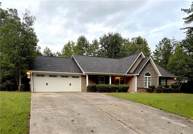 a view of white house with a big yard and large trees