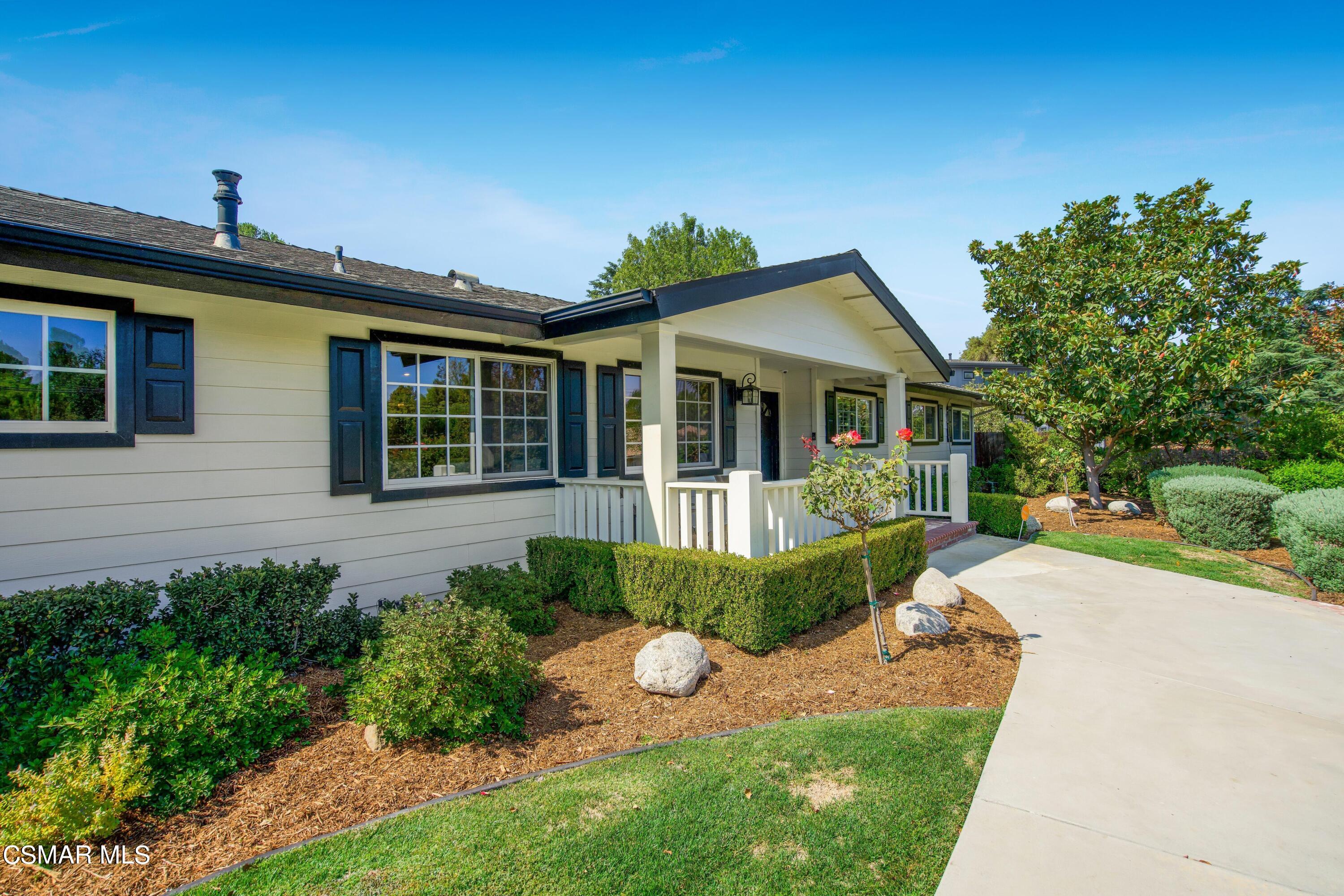 a front view of a house with a yard and potted plants
