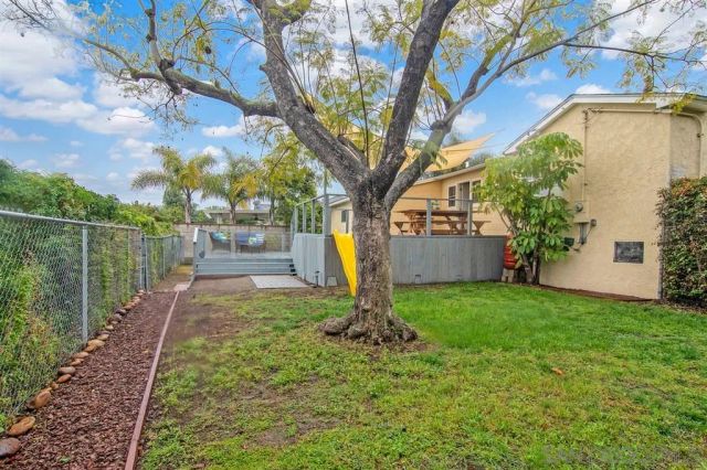 a view of a backyard with large tree and wooden fence