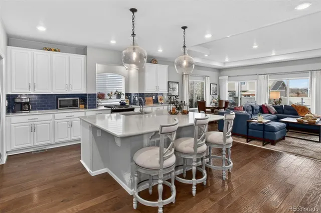 an open kitchen with granite countertop a white cabinets and chairs
