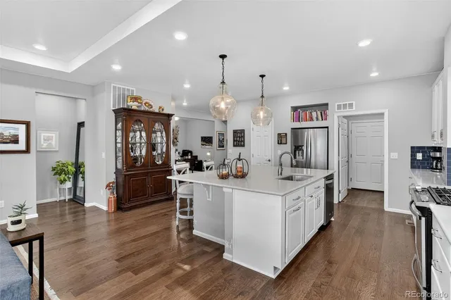 a kitchen that has a lot of white cabinets and stainless steel appliances
