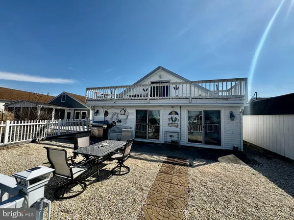 a view of a house with a wooden deck and a barbeque