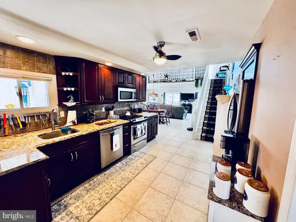 a large kitchen with stainless steel appliances granite countertop a sink stove and refrigerator