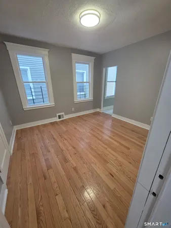 a view of an empty room with wooden floor and a window