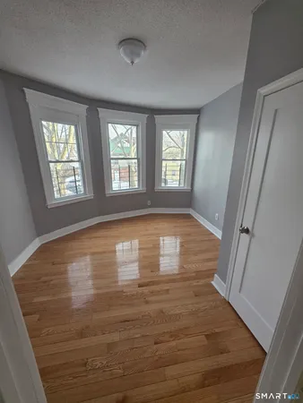 a view of empty room with wooden floor and fan