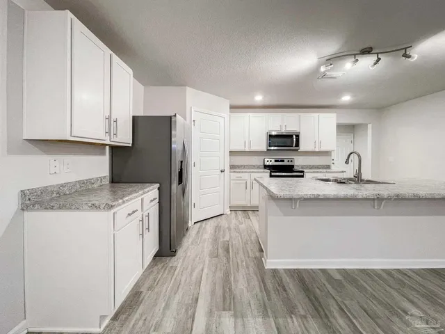 a kitchen with granite countertop a refrigerator stove top oven and cabinets