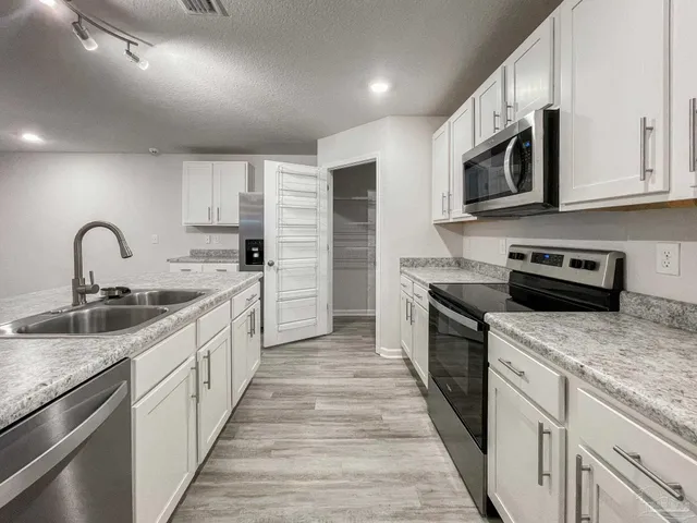 a large kitchen with stainless steel appliances granite countertop a sink and dishwasher a stove top oven with wooden floor