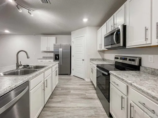 a kitchen with stainless steel appliances granite countertop a sink stove microwave and refrigerator