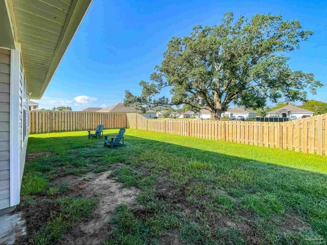 a view of a backyard with table and chairs with wooden fence