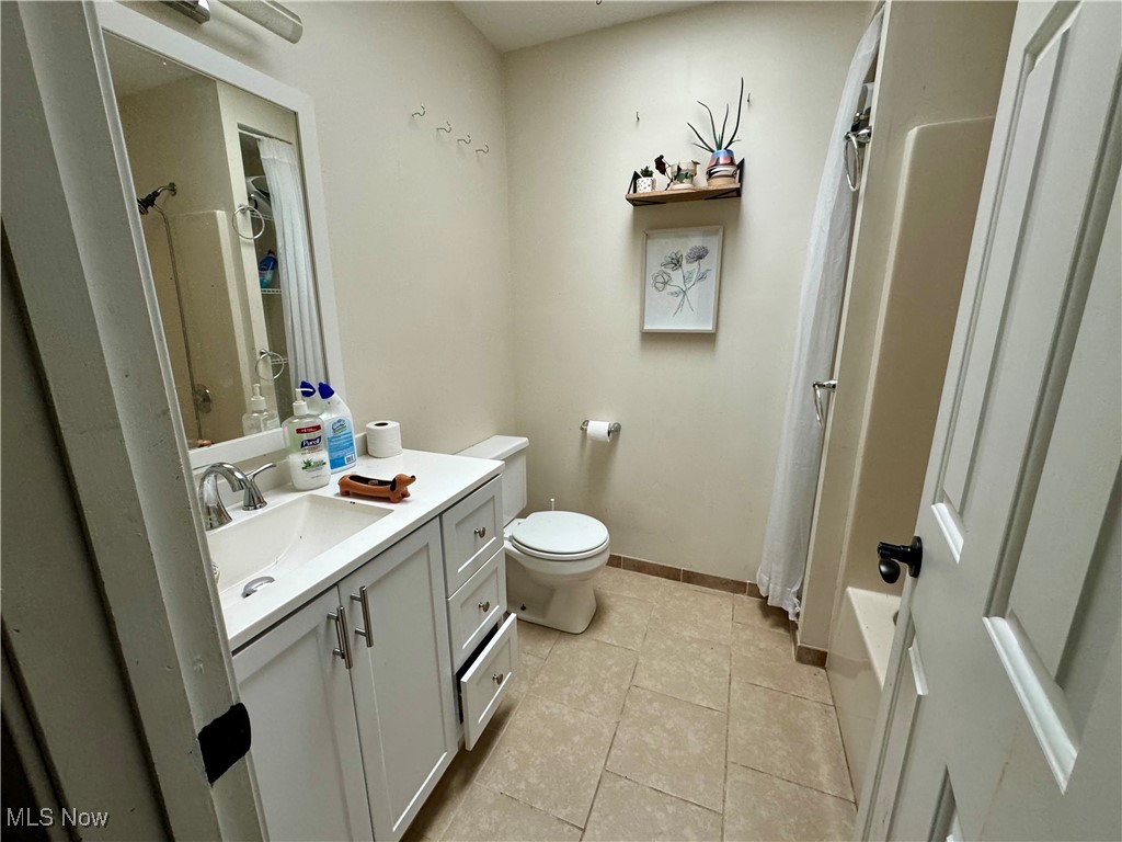 1425 Bennett Road Madison, OH 44057 - Photo 16 of 17 Full bathroom with shower / bath combination with curtain, tile patterned flooring, vanity, and toilet
