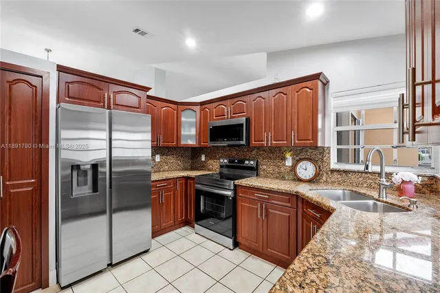 a kitchen with stainless steel appliances granite countertop a stove top oven sink and refrigerator