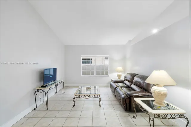 a living room with furniture a flat screen tv and a window