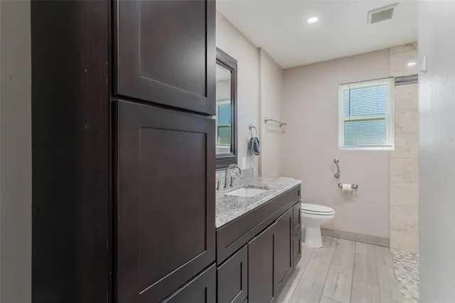 a bathroom with a granite countertop sink toilet and shower curtains