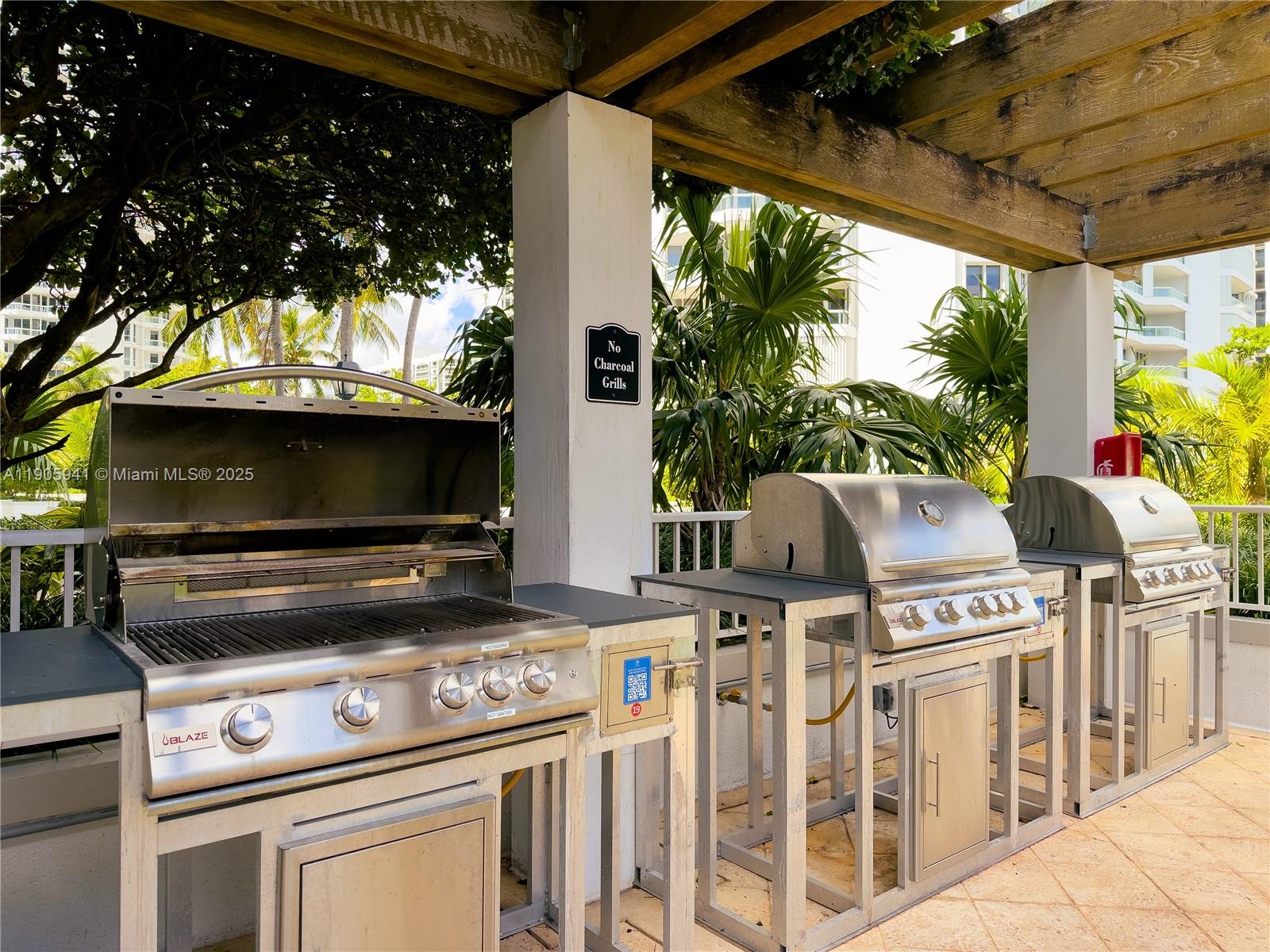 21050 Point Place, Unit 401 Aventura, FL 33180 - Photo 29 of 40 a view of a patio with table and chairs a barbeque with a small yard