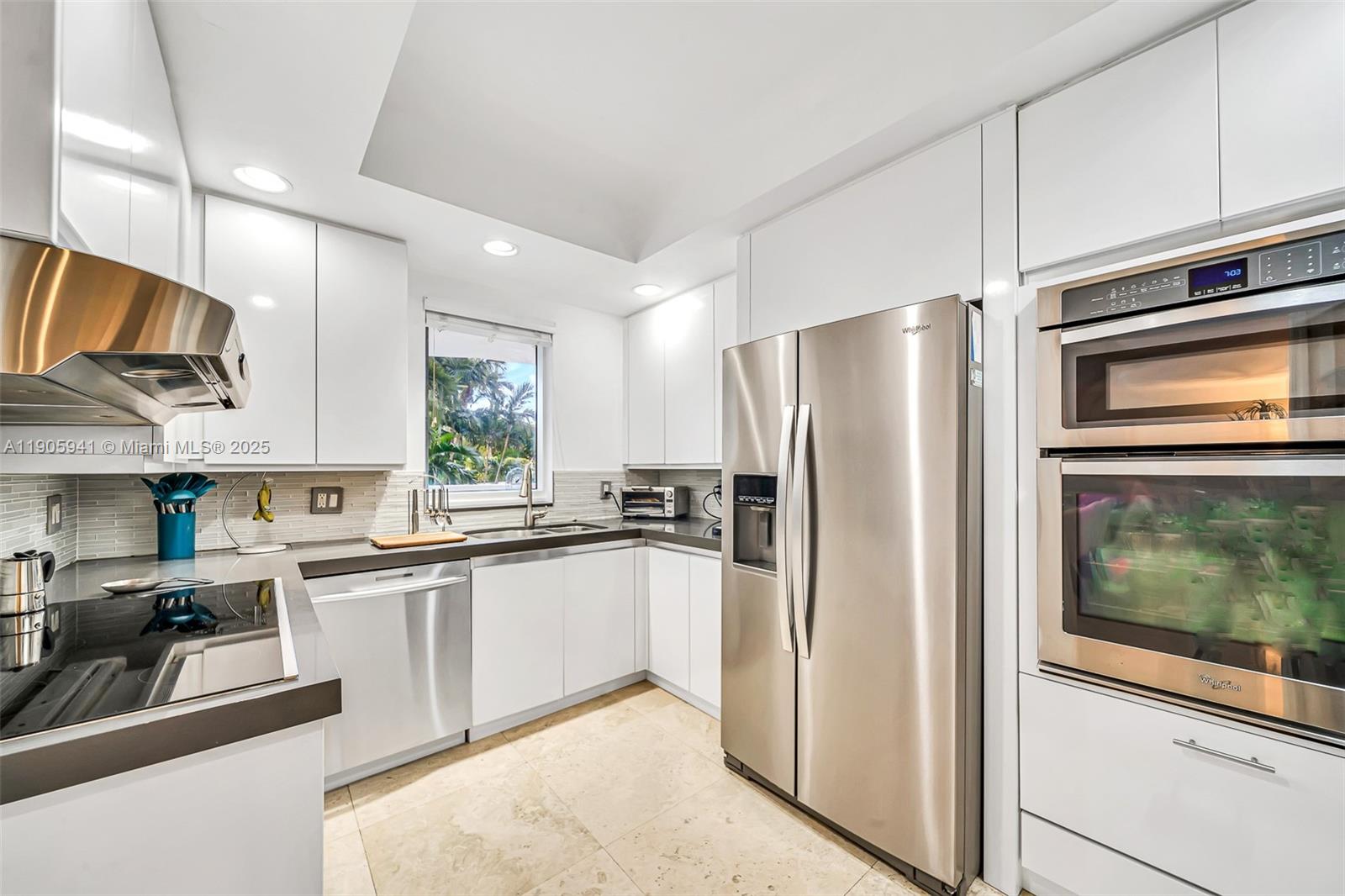 21050 Point Place, Unit 401 Aventura, FL 33180 - Photo 10 of 40 a kitchen with stainless steel appliances granite countertop a refrigerator a stove a sink and a microwave