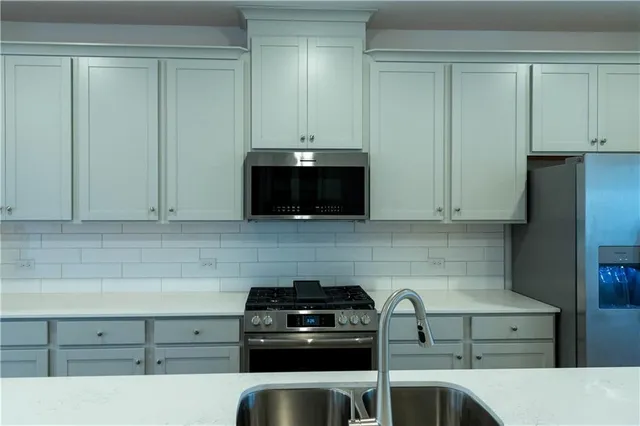 a kitchen with granite countertop white cabinets and stainless steel appliances