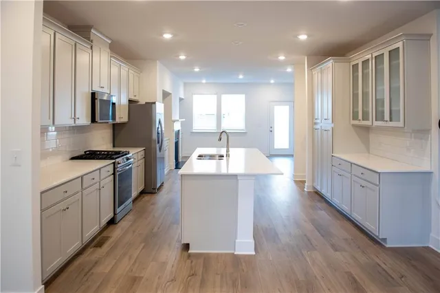 a large kitchen with stainless steel appliances lots of counter space and wooden floor