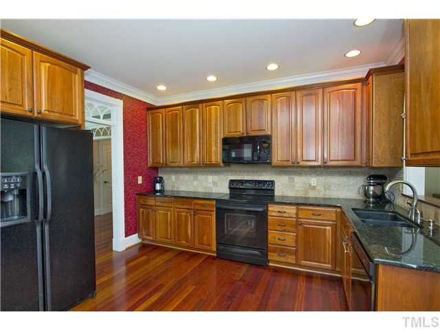 6816 Pinnacle Ridge Road Raleigh, NC 27603 - Photo 6 of 24 Well appointed kitchen with cherry cabinets and floors. Notice the beautiful transoms above the doorway. Beautiful tile backsplash. Kitchen