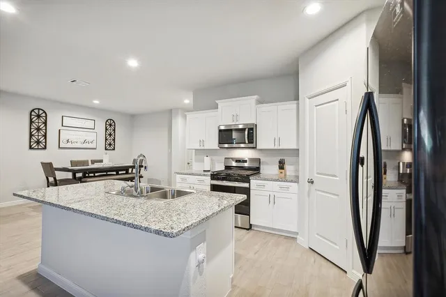 a kitchen with stainless steel appliances granite countertop a refrigerator a stove a sink a microwave and a refrigerator