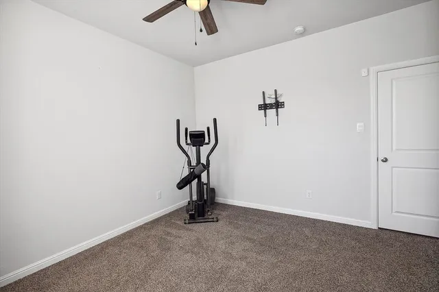 an empty room with a chandelier fan and wooden floor