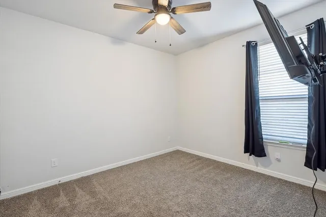 an empty room with a ceiling fan and carpet