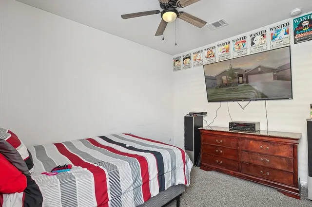 a bedroom with a bed and a flat tv screen on dresser
