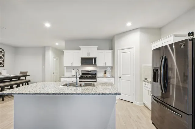 a kitchen with stainless steel appliances granite countertop a refrigerator a stove and a sink