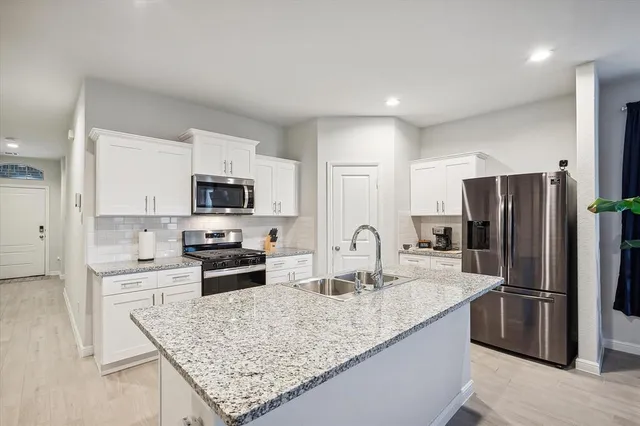 a kitchen with stainless steel appliances granite countertop a sink stove and refrigerator
