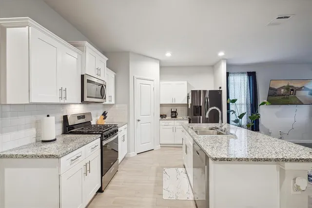 a kitchen with granite countertop a sink stove top oven and refrigerator