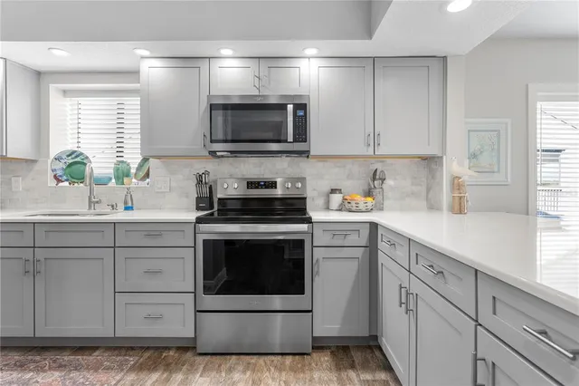 a kitchen with white cabinets stainless steel appliances and window