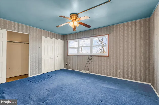 an empty room with chandelier fan and windows