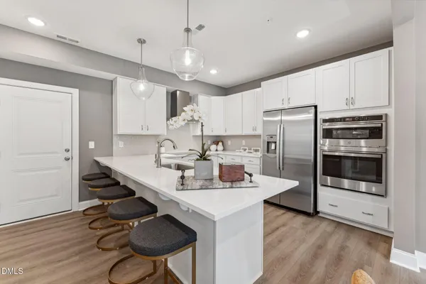 a kitchen with stainless steel appliances granite countertop a sink a stove a refrigerator and island with wooden floor