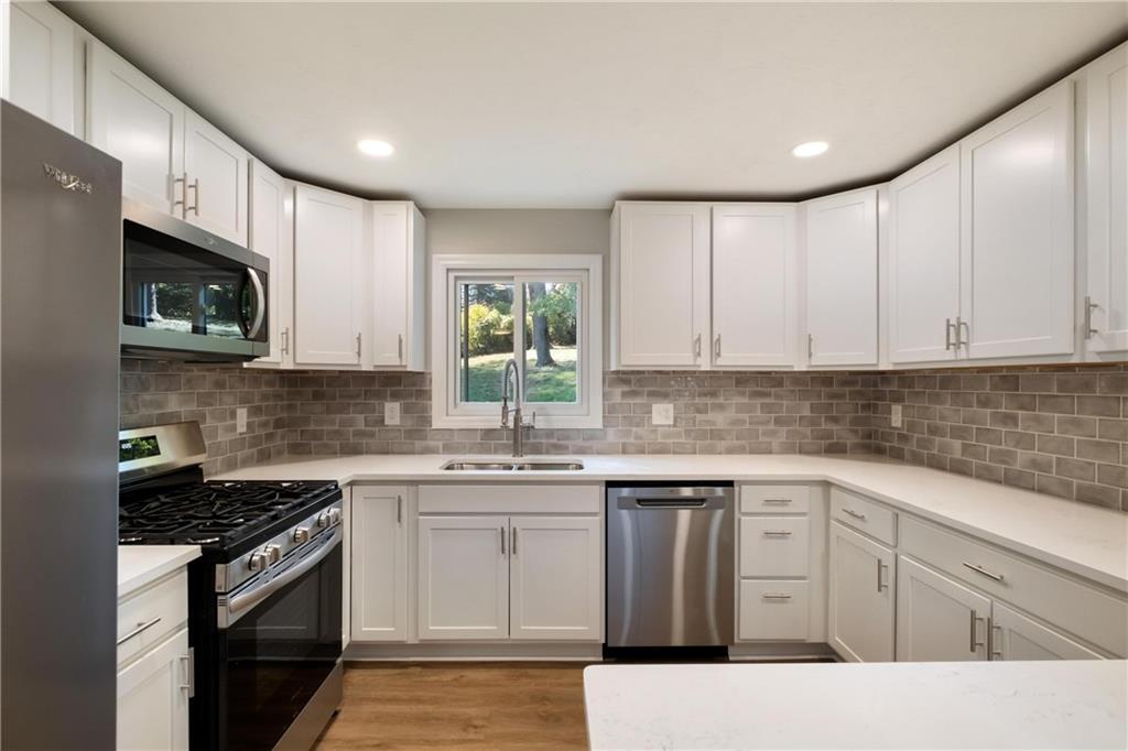 4786 Doyle Road Pittsburgh, PA 15227 - Photo 10 of 31 a kitchen with stainless steel appliances granite countertop a sink dishwasher stove and white cabinets with wooden floor