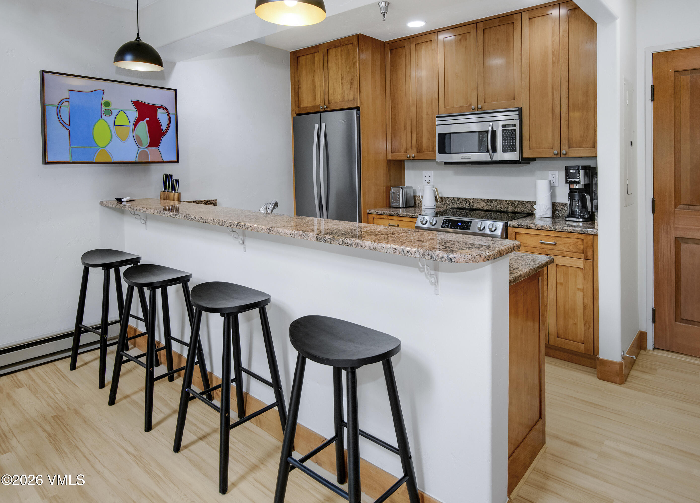 1206 Village Road, Unit B307 Beaver Creek, CO 81620 - Photo 5 of 20 a kitchen with stainless steel appliances a microwave a stove a refrigerator and a dining table with wooden floor