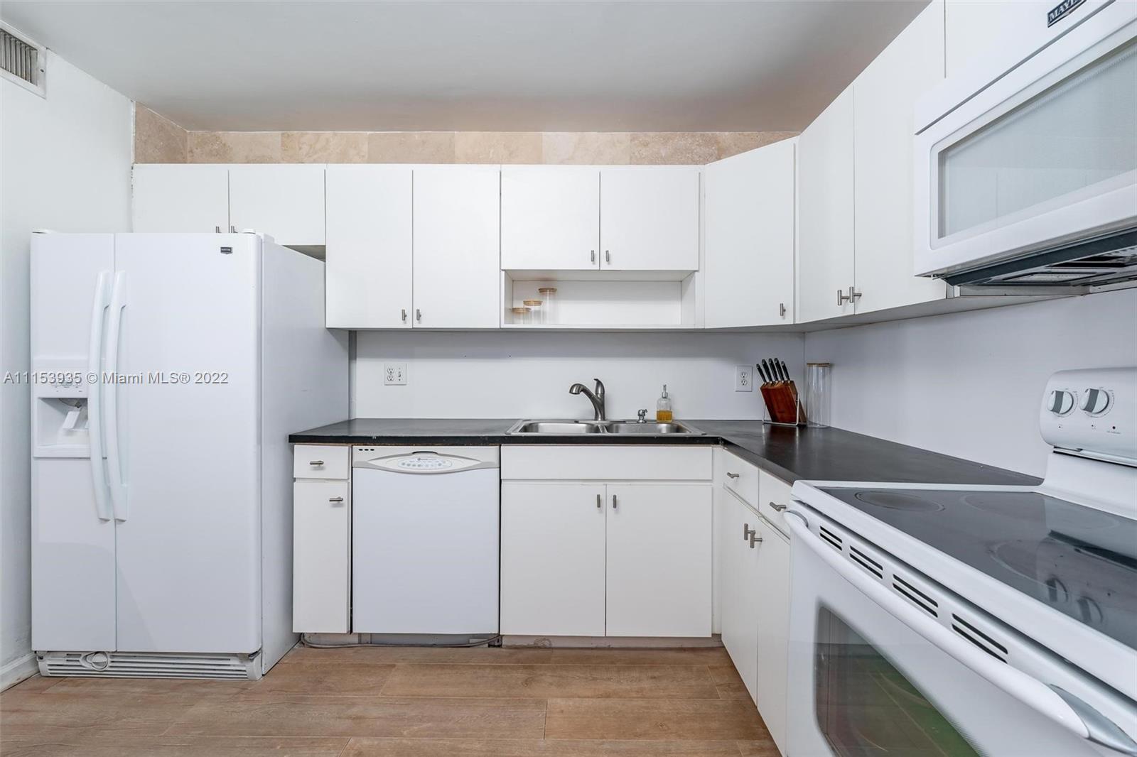 200 Southeast 15th Road, Unit 11H Miami, FL 33129 - Photo 13 of 20 a kitchen with white cabinets and white appliances