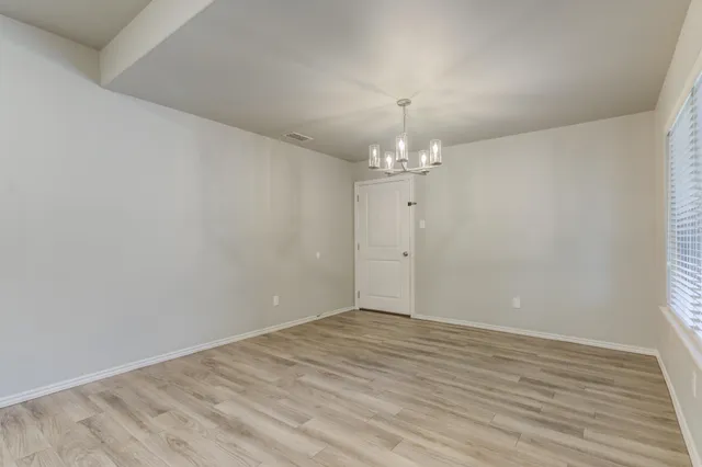 an empty room with wooden floor and chandelier