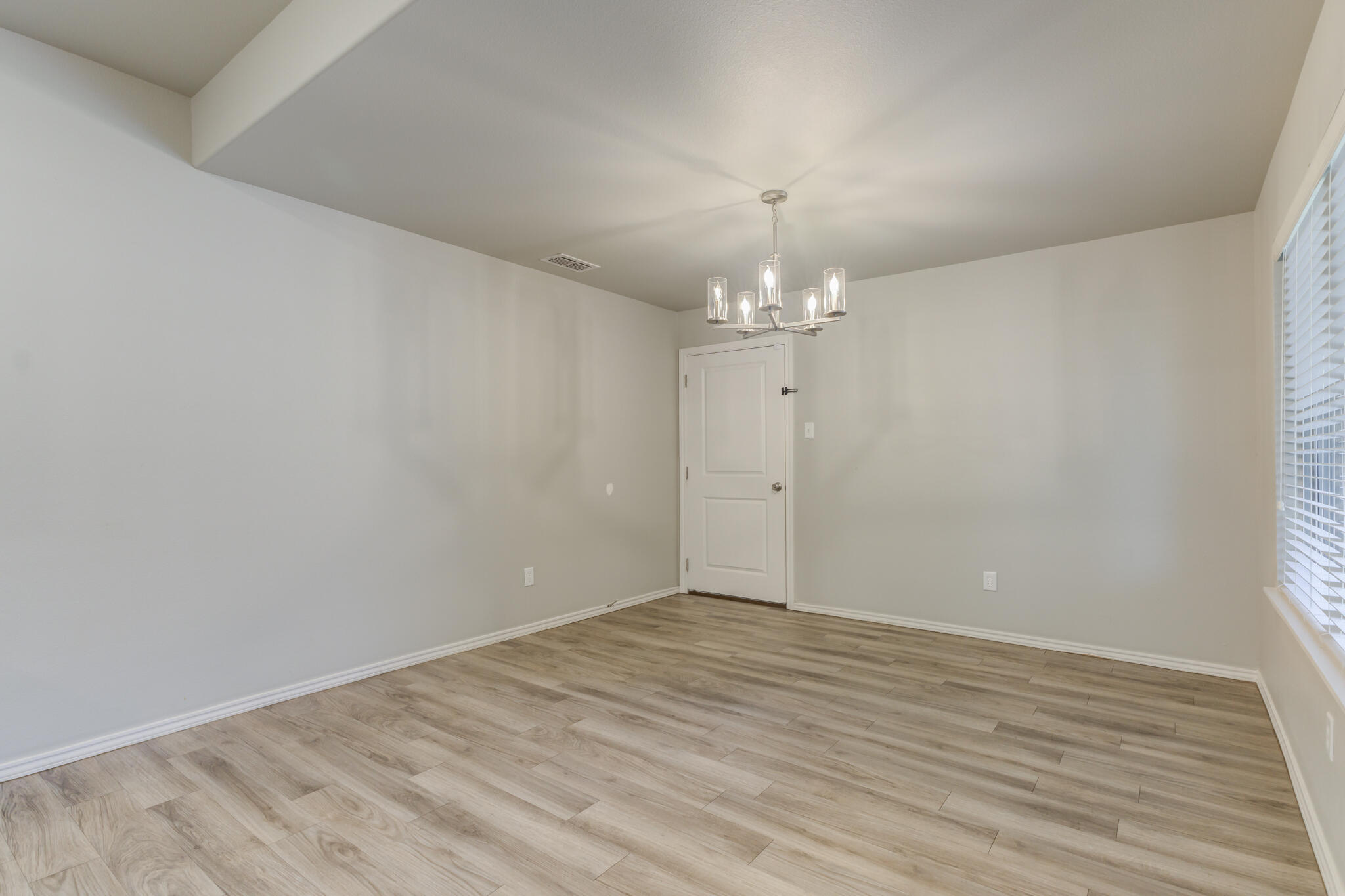 6906 67th Street Lubbock, TX 79424 - Photo 12 of 35 an empty room with wooden floor and chandelier