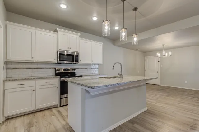 a kitchen with kitchen island granite countertop a sink a counter space appliances and cabinets